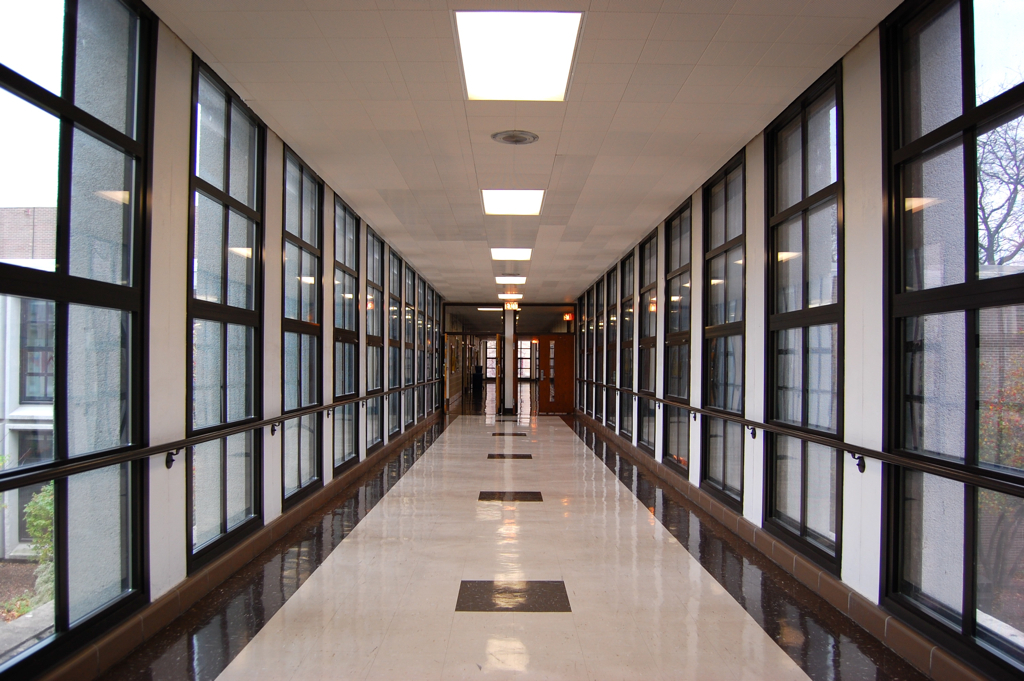 A bright modern school hallway with tall windows and a polished tile floor